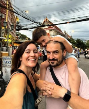 Selfi de la familia sonriendo en una calle de Tailandia, con su hijo subido a hombros